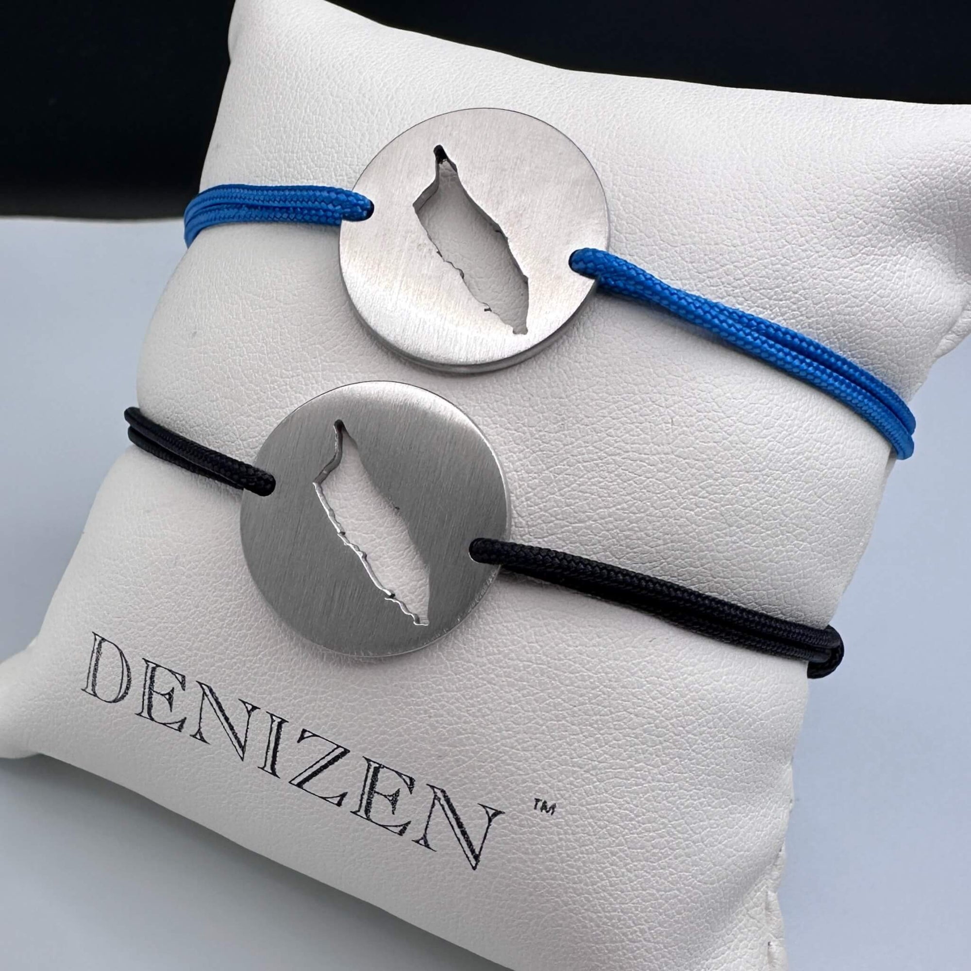 Two DENIZEN brushed steel bracelets with an Aruba map cutout on black and blue strings