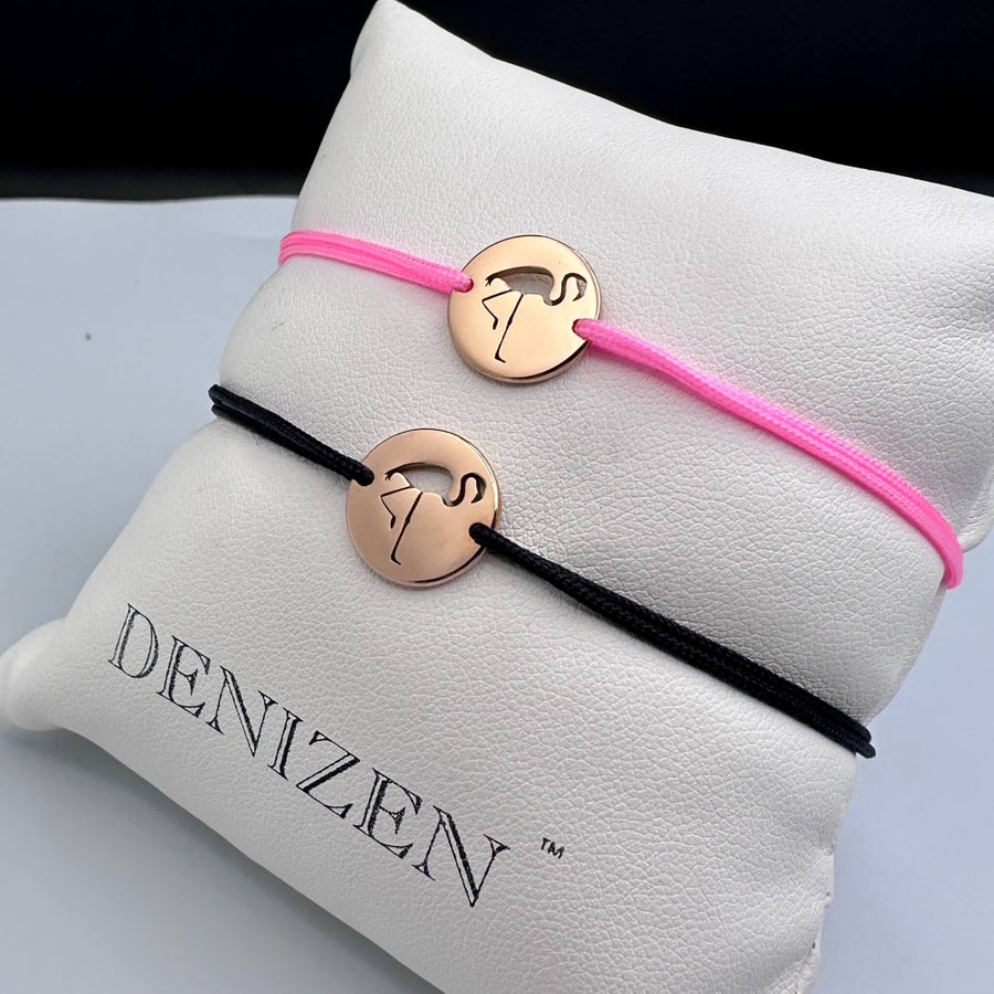 Two DENIZEN small rose gold bracelets with a cutout of a flamingo on black and pink strings