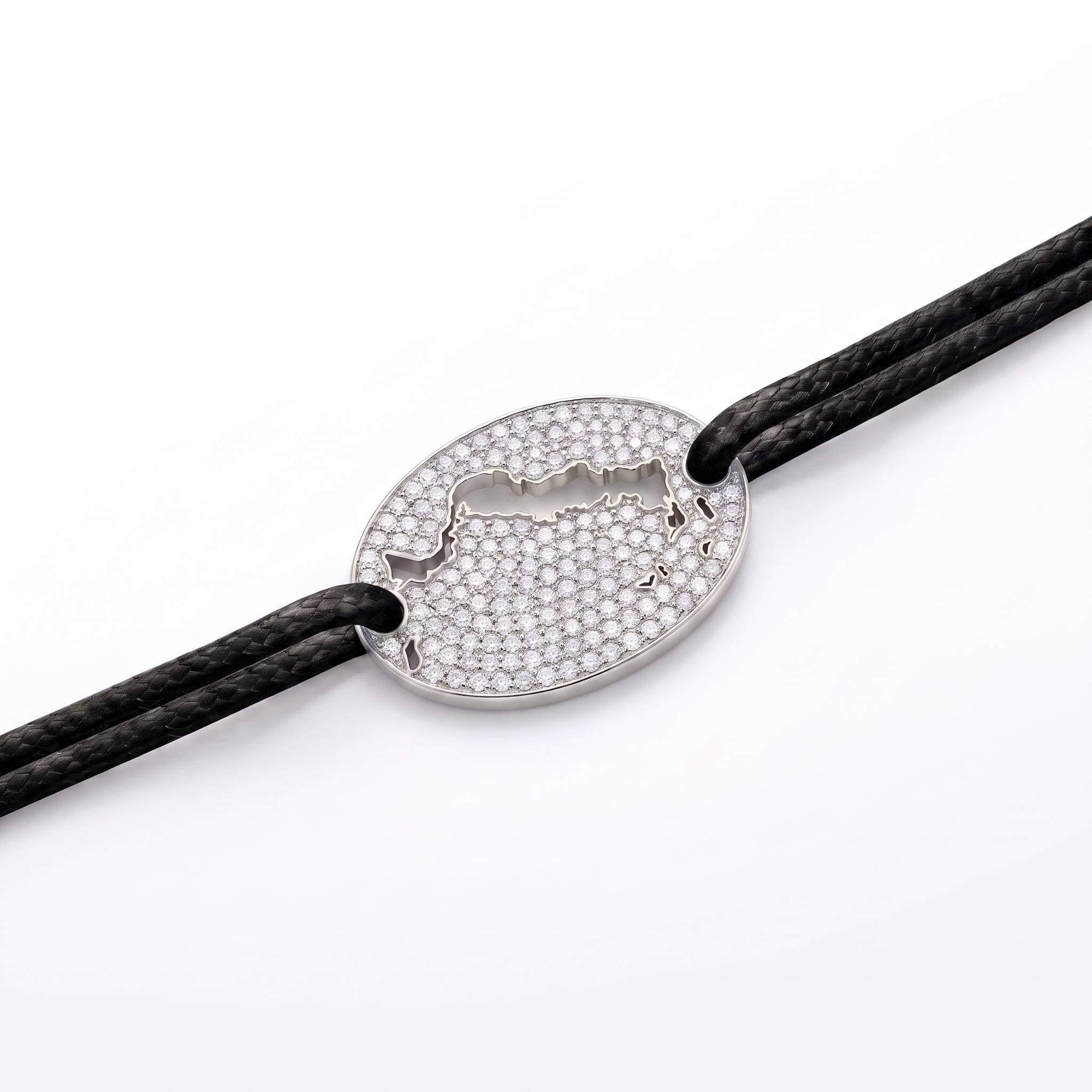 A silver oval bracelet featuring a cutout of the Turks and Caicos map paved with small clear stones, threaded on a black cord against a white background.